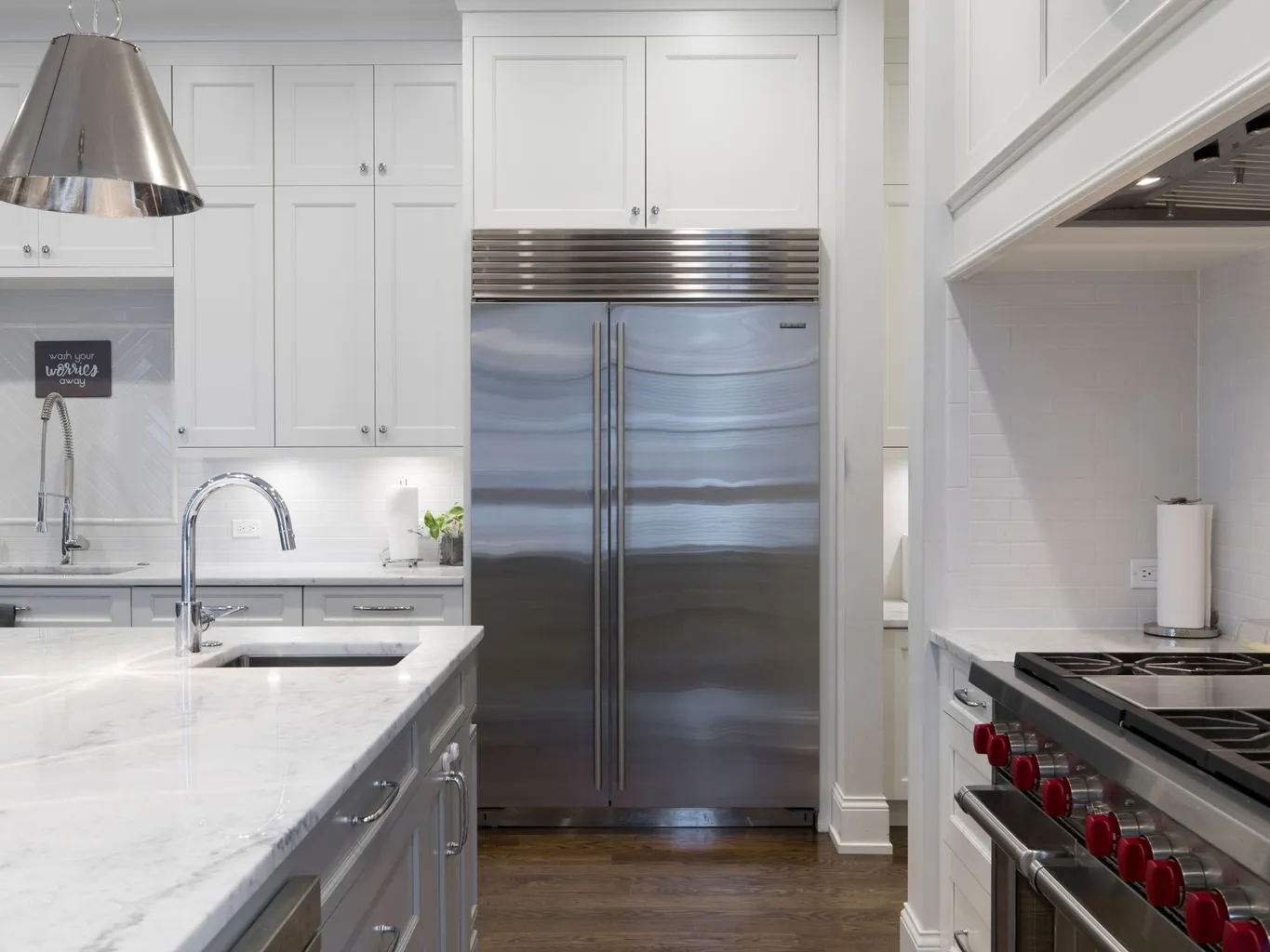 A clean home kitchen with a large stainless steel refrigerator and a professional gas range