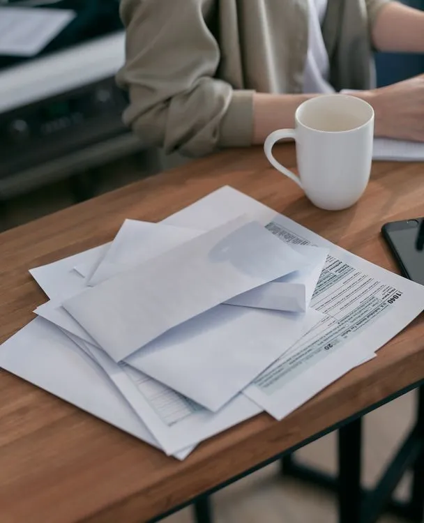 White envelopes and tax return documents on a wooden table with coffee