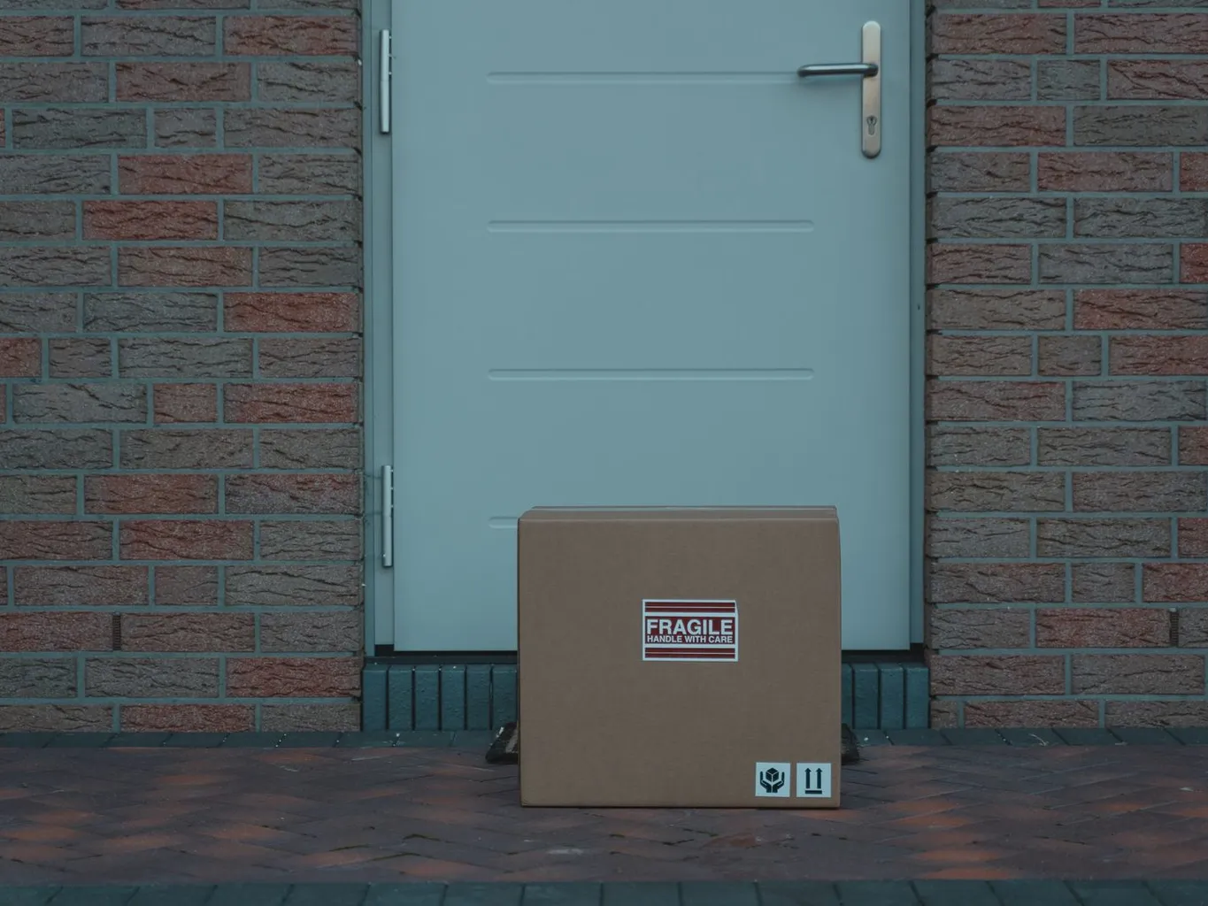 A cardboard delivery box marked fragile sitting on a doorstep in front of a door